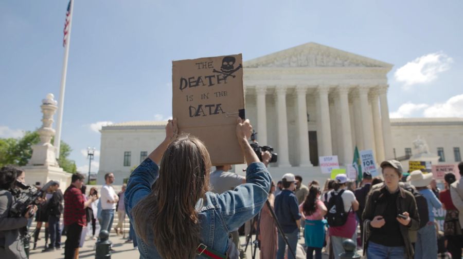 A protester holds up a sign reading “The death is in the data” outside the US Supreme Court