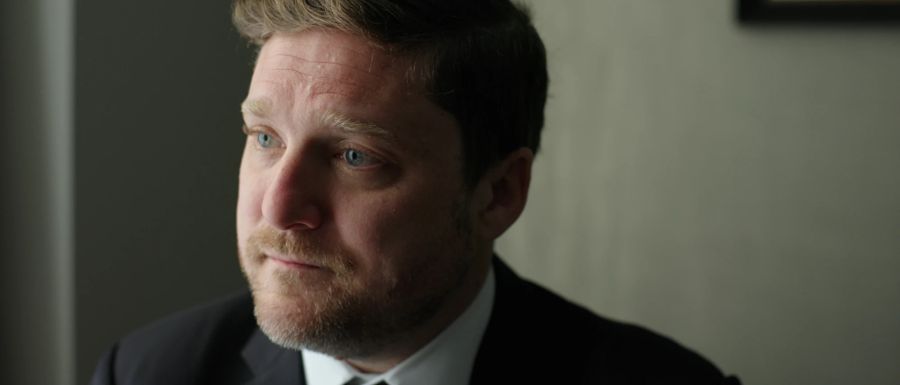 A man in a suit looks toward a window
