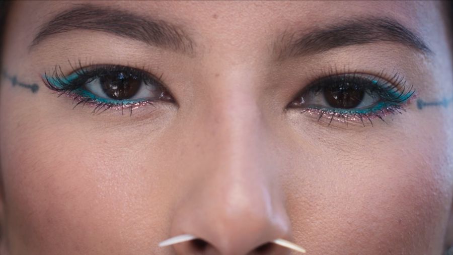 Close-up of eyes with teal eyeliner and traditional facial markings