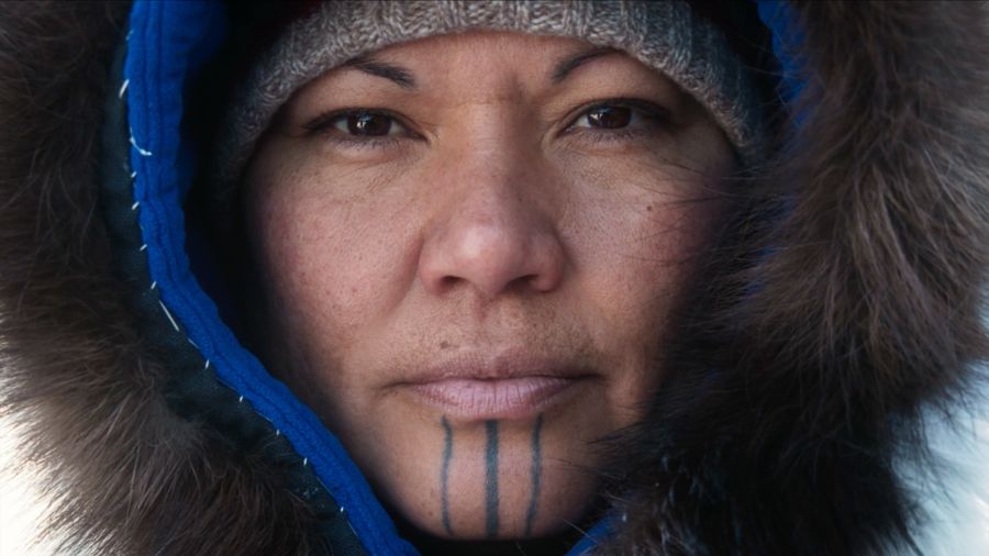A woman with traditional chin tattoos, framed by a fur-lined hood