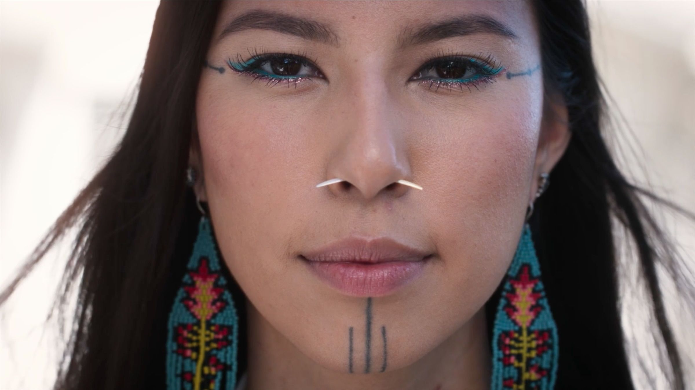Quannah Chasinghorse with traditional facial markings and beaded earrings