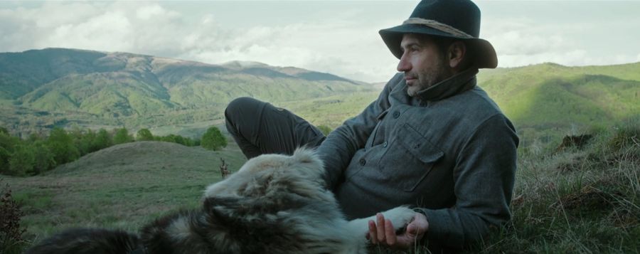 A man in a hat with a dog on a Carpathian hillside